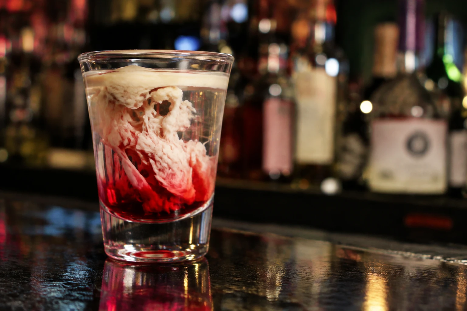 Verre à shot de cocktail cervelle de singe avec filaments blancs dans un liquide rouge et transparent